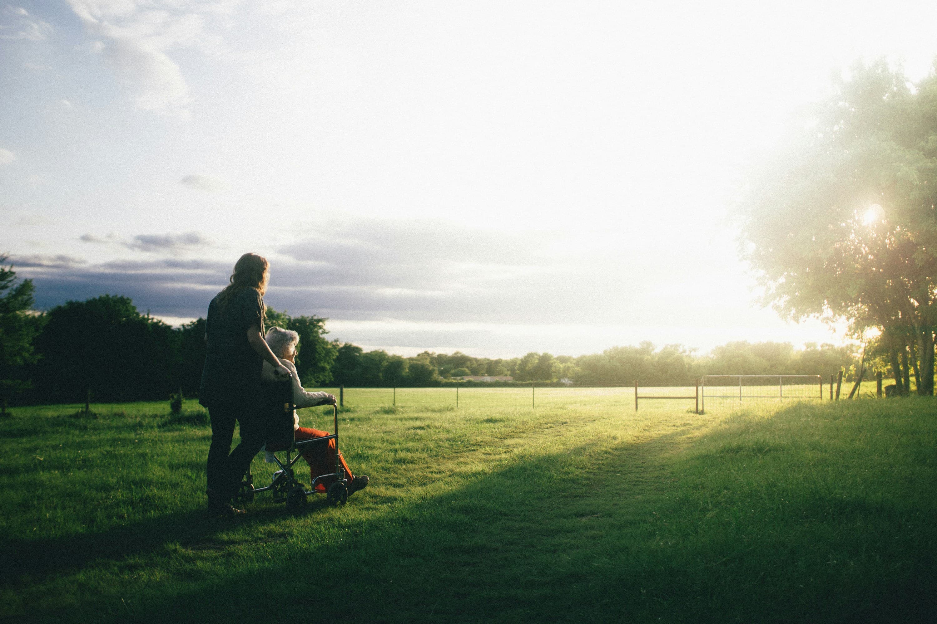 Caregiver and elderly person enjoying a peaceful sunset walk